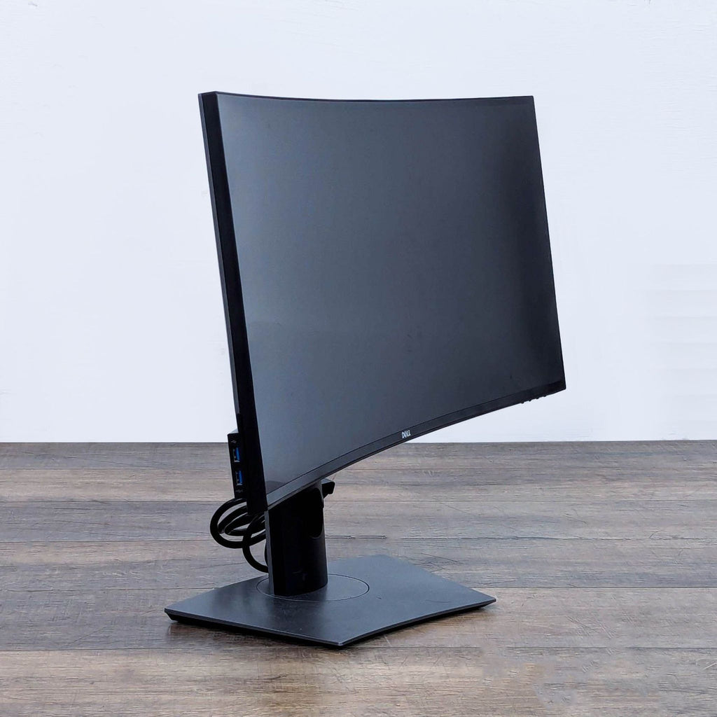 Dell curved monitor with a notification on the screen, set on a wooden table.