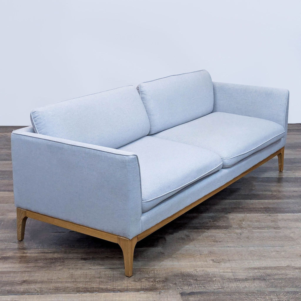 3. Angled view of Rove Concepts sofa featuring piped cushions and ash wood legs for stylish support.