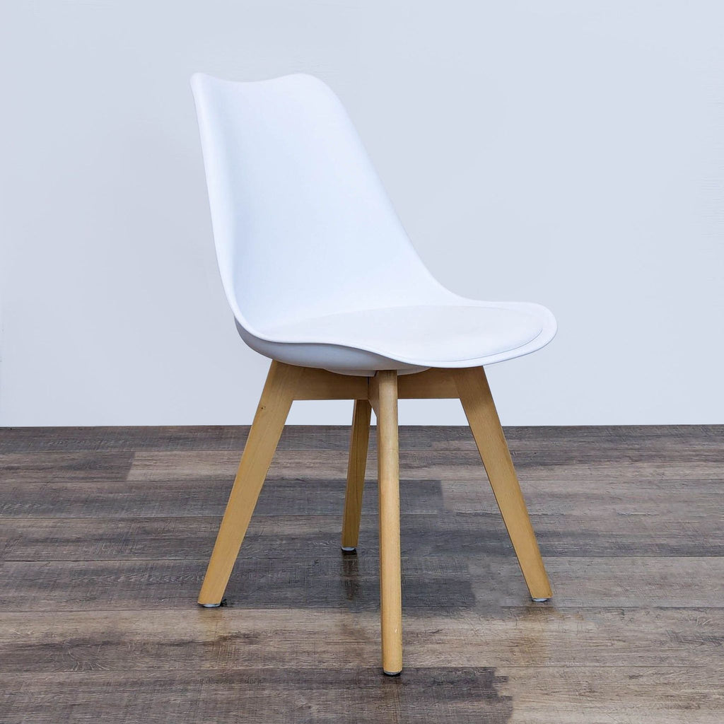 Side angle of a white dining chair, padded seat, wood legs, by Reperch.
