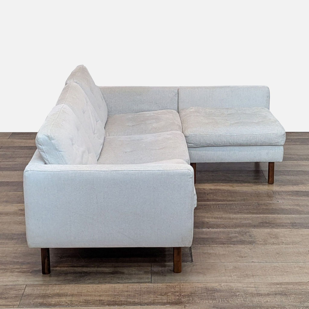 Side view of a modern Reperch chaise sofa in light fabric, showcasing high-density foam cushions and walnut wood legs.