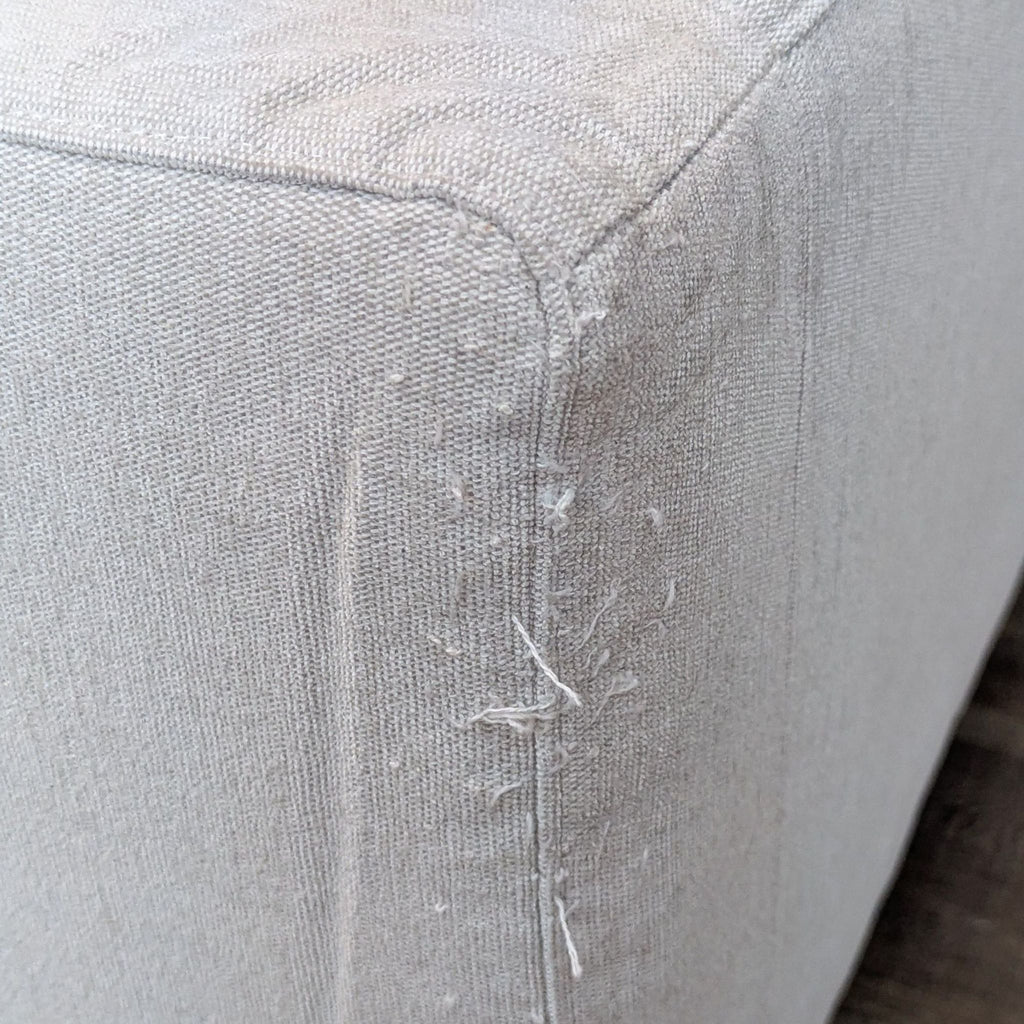 Close-up of fabric texture on a sofa corner, highlighting wear details.
