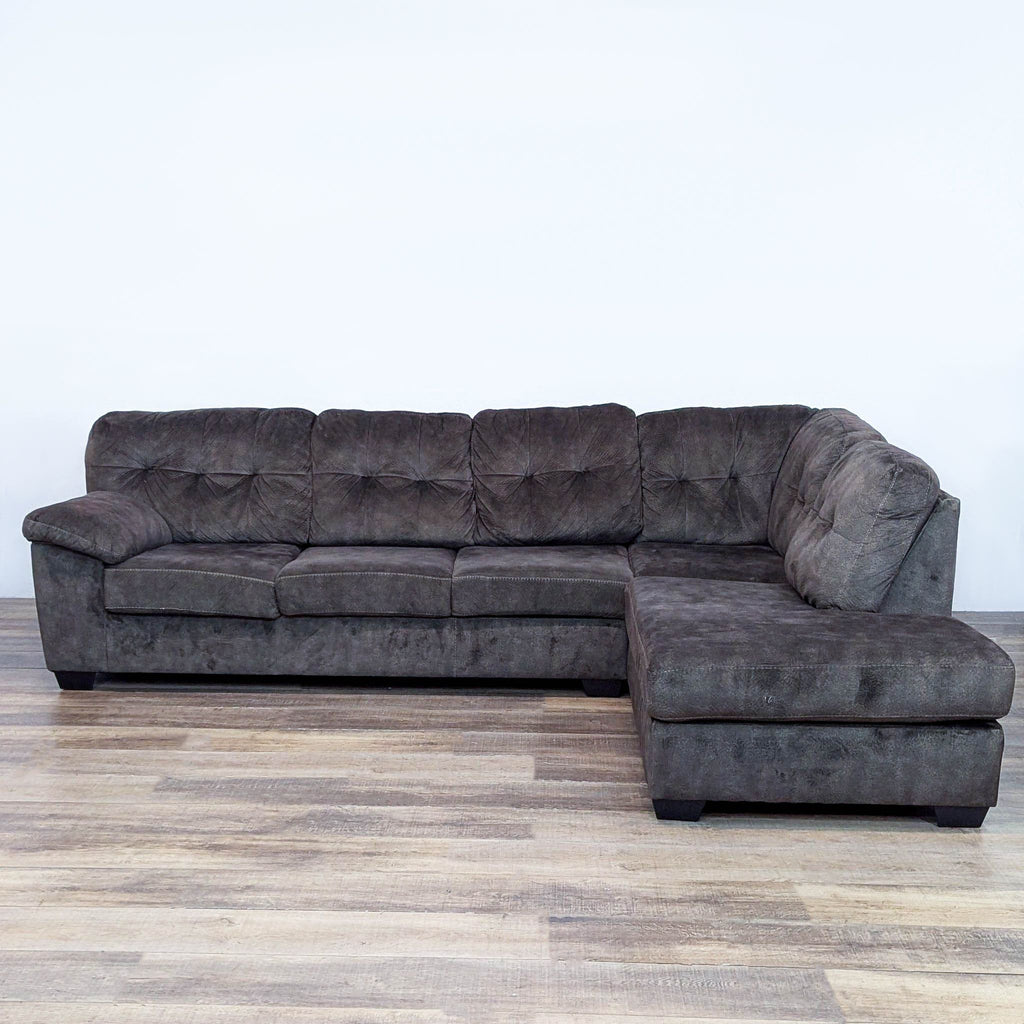 Tufted box-cushioned sectional with pillow top armrests on hardwood floor.