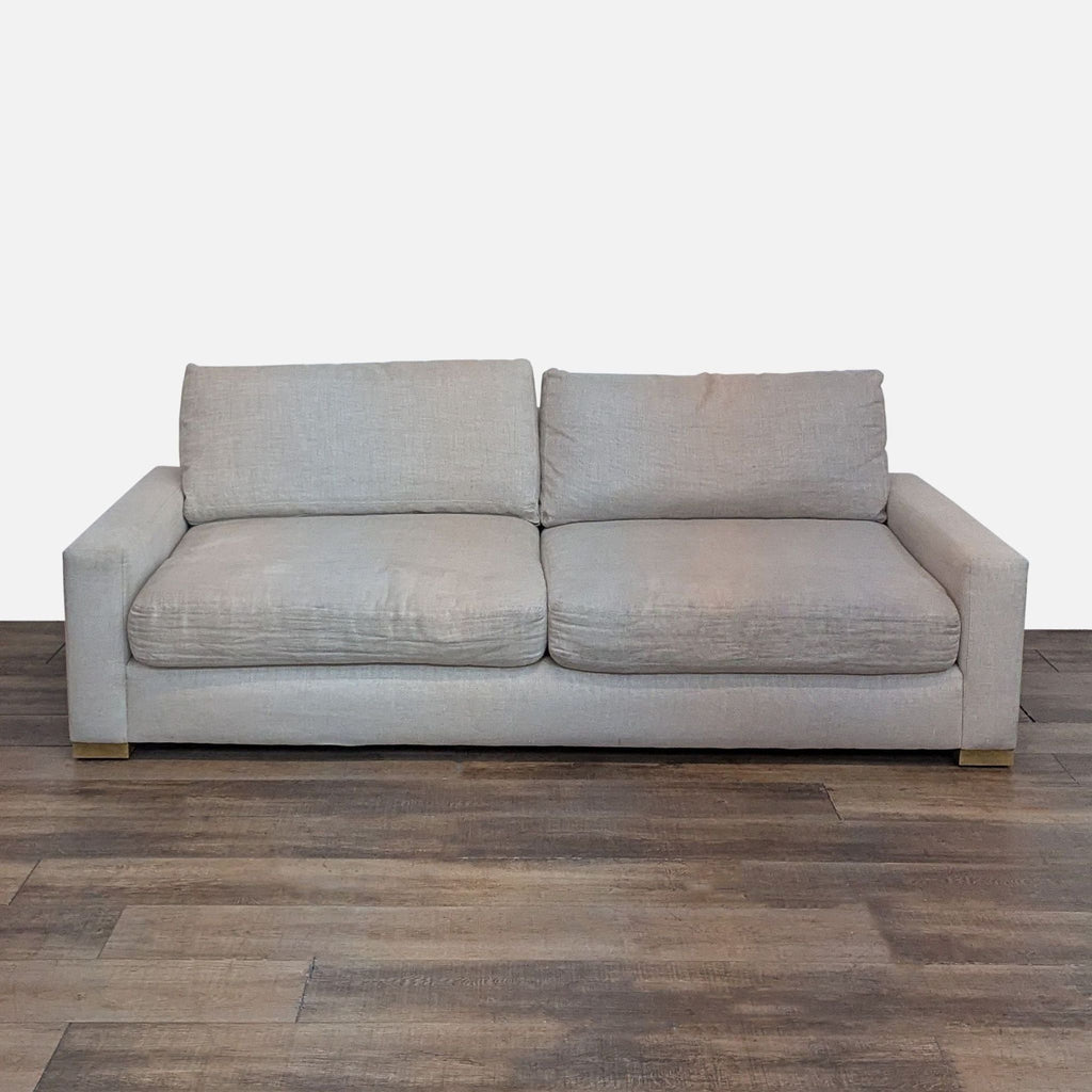 Restoration Hardware loveseat in beige with plush cushions on wood flooring.