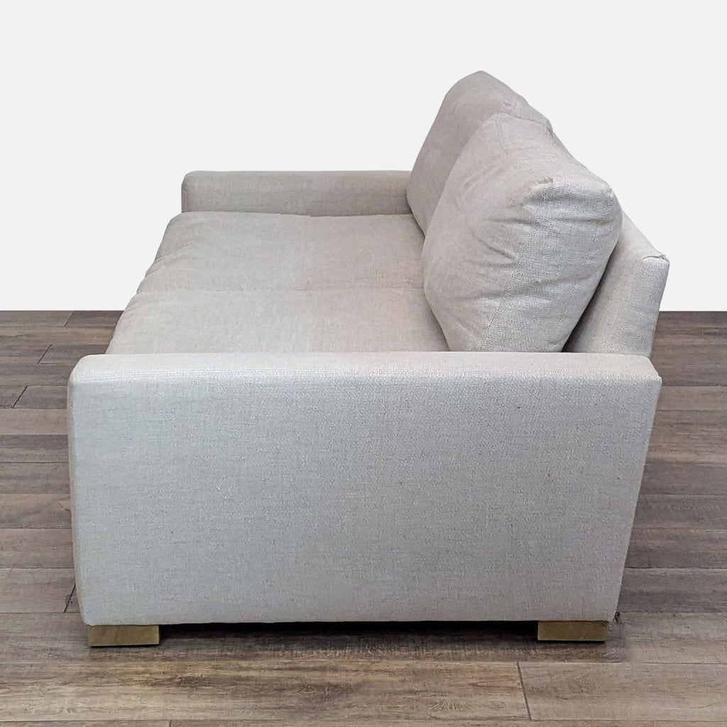 Side view of a beige Restoration Hardware loveseat on wood floor.
