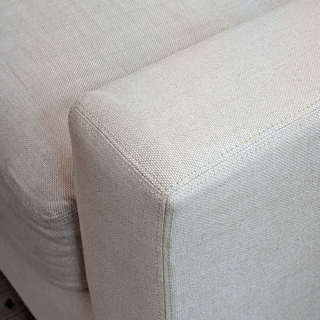 Close-up of a Restoration Hardware loveseat's beige fabric and stitching.