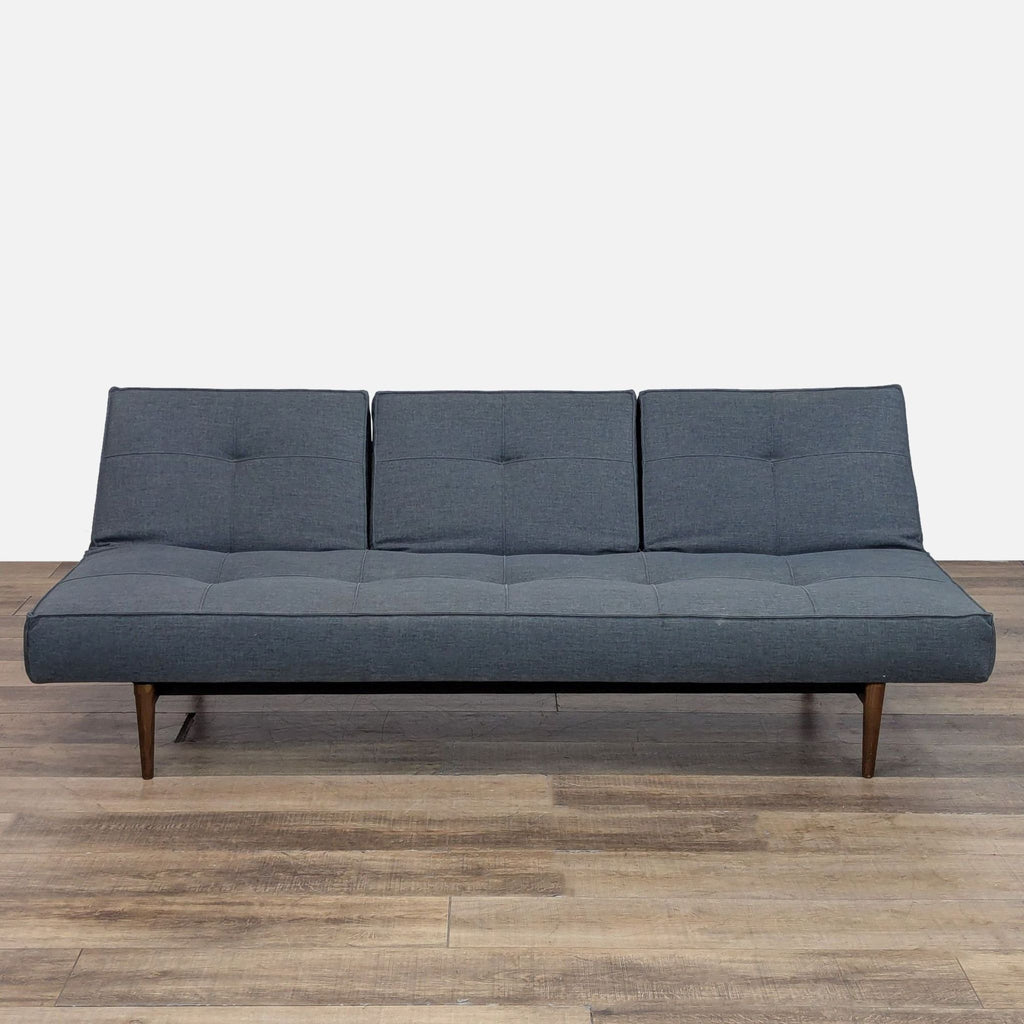Mid-century sleeper sofa with tufted cushions and tapered legs, shown upright.