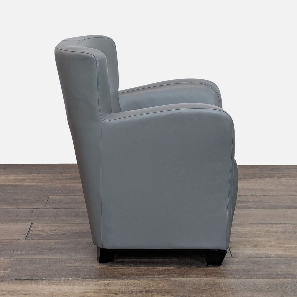 Side view of gray lounge chair featuring rounded arms and tapered wood feet. Faux leather upholstery.