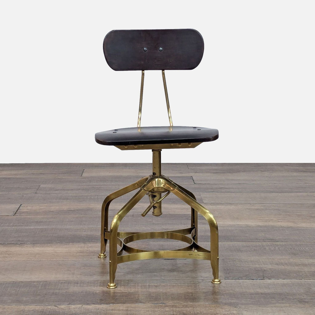 Reproduction vintage draftsman’s chair with brass finish, wood seat, and adjustable steel base.
