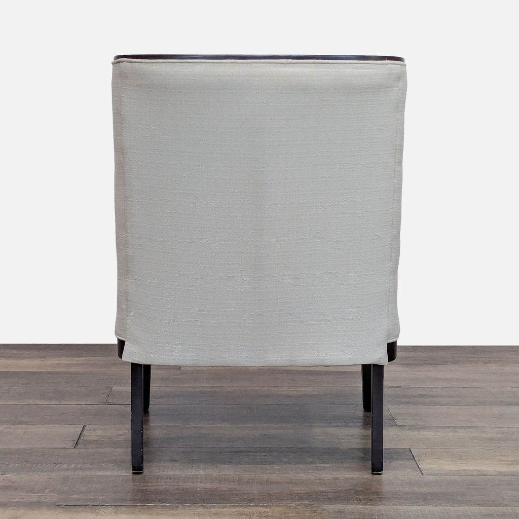 Back view of a Bloomingdale’s lounge chair in light fabric with a dark wood frame.