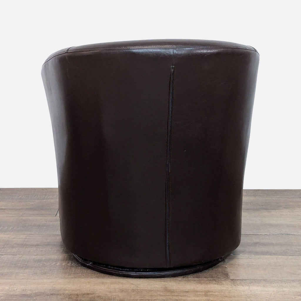 Rear view of brown faux leather barrel back chair on a swivel base.