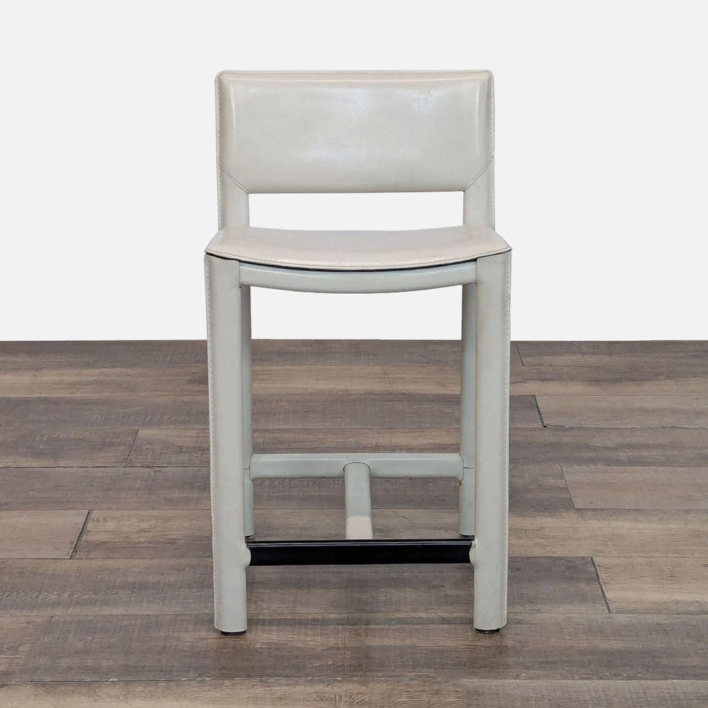 Modern stool with metal footrest and cushioned back, viewed from the front.