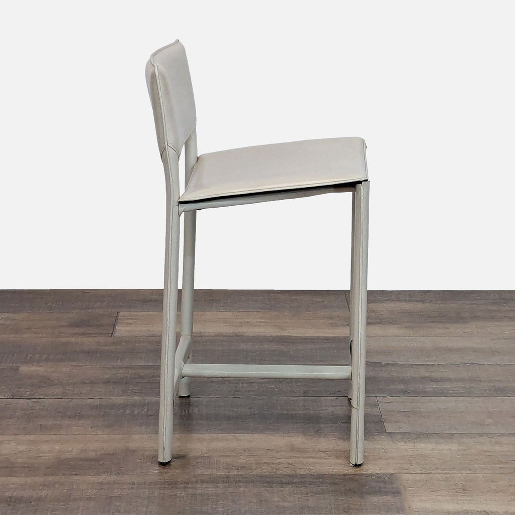 Profile view of a minimalist stool with a padded seat and back.