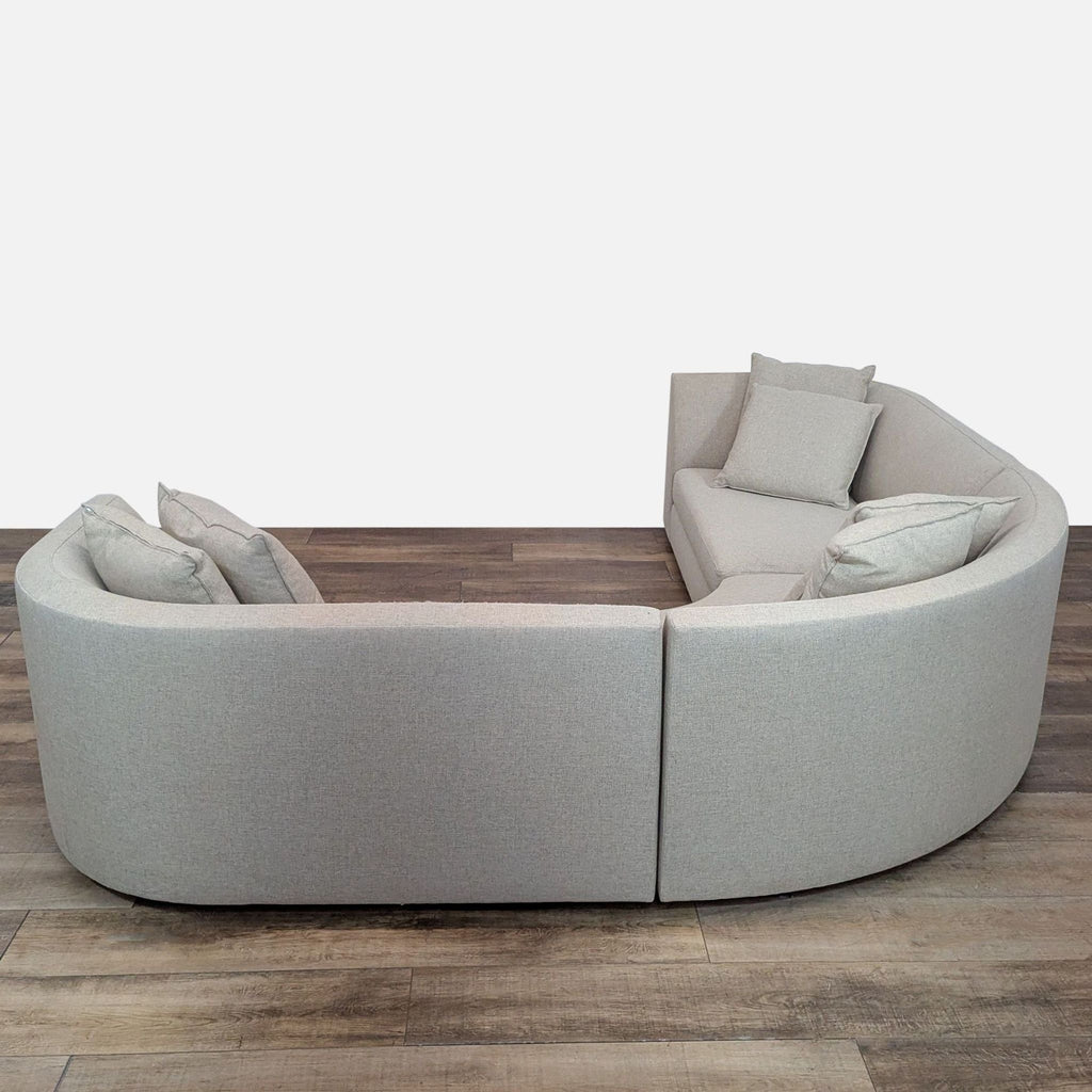 Curved Room & Board sectional with plush back pillows, offering stylish and comfortable seating.