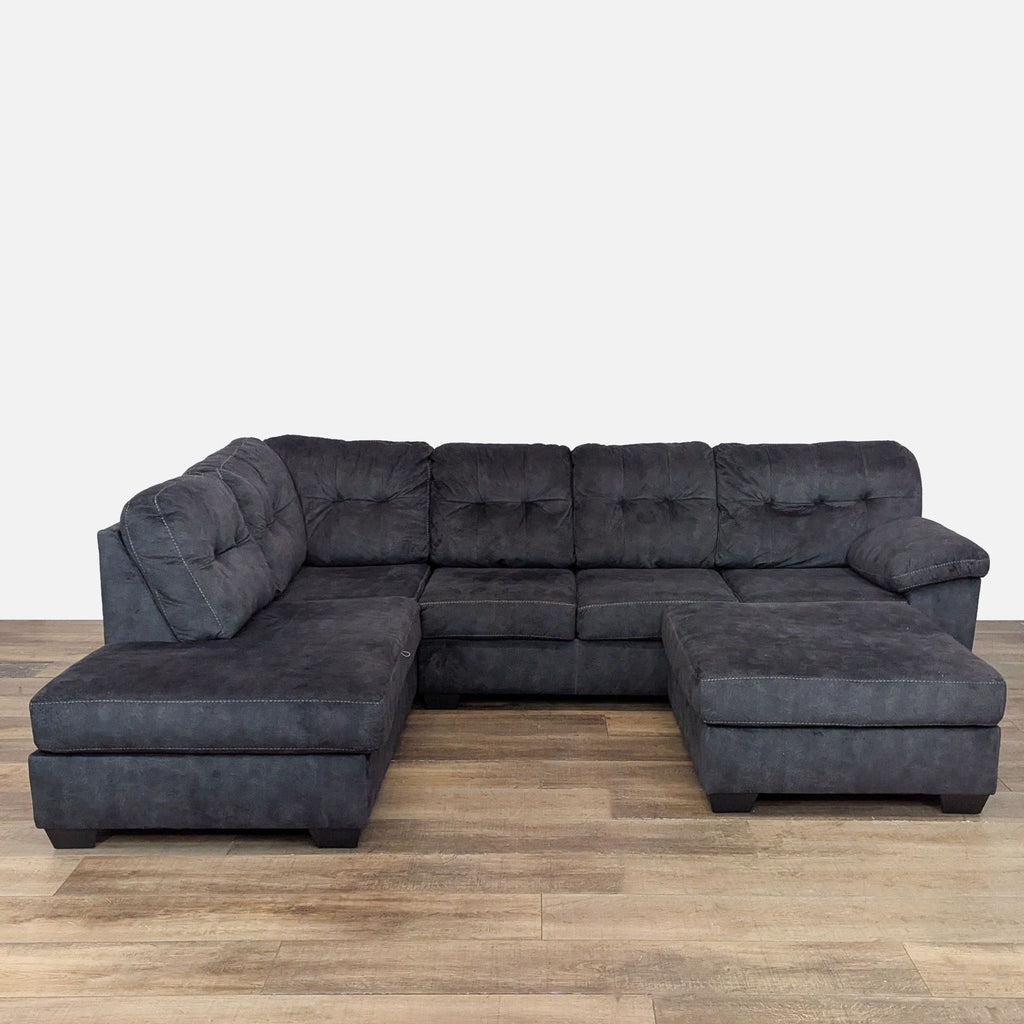 Gray sectional sofa with tufted box cushioning and thick pillow top armrests.