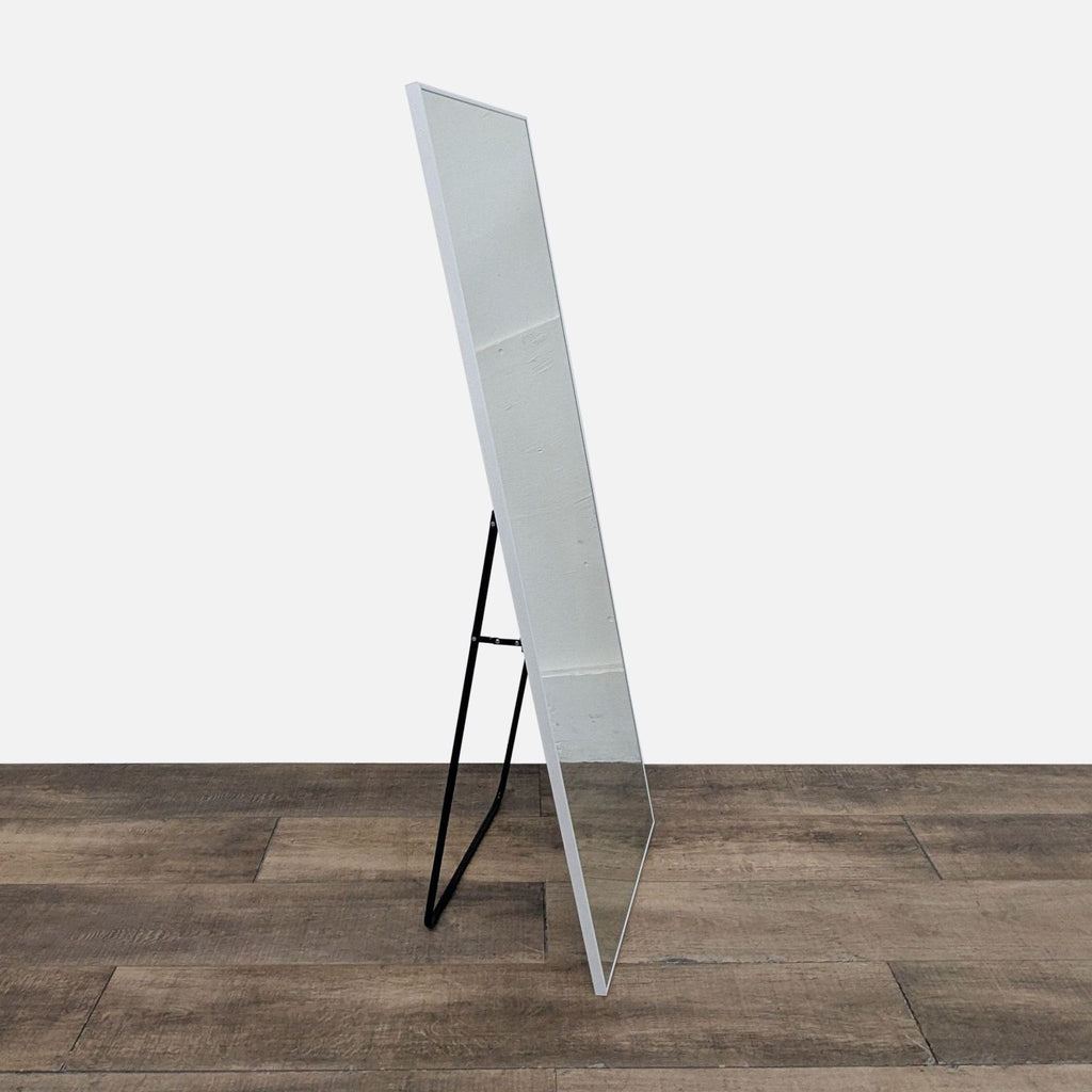 Side view of a slim mirror with black stand.