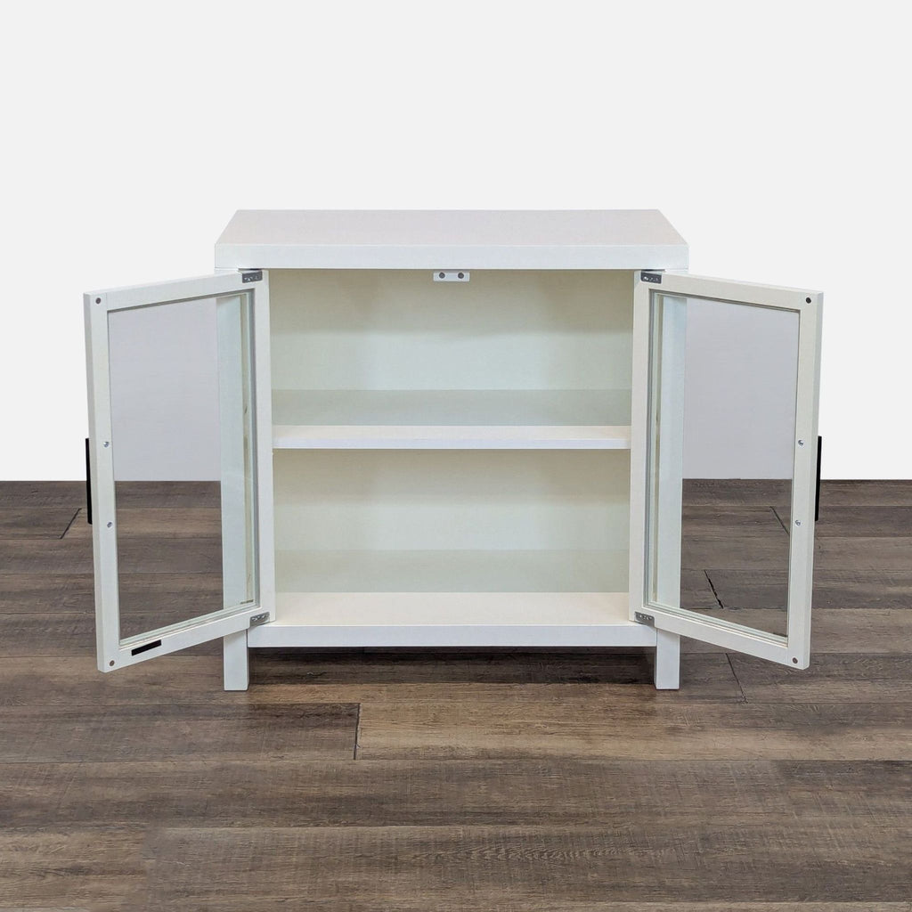 Open cabinet showing interior shelf, framed with glass doors, on a wood floor.