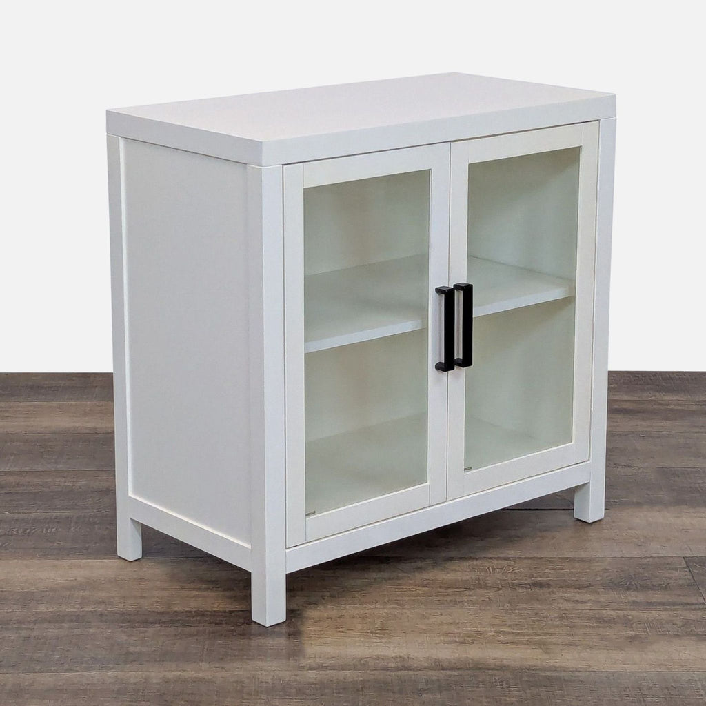Corner view of a white cabinet with glass doors and a single shelf inside.