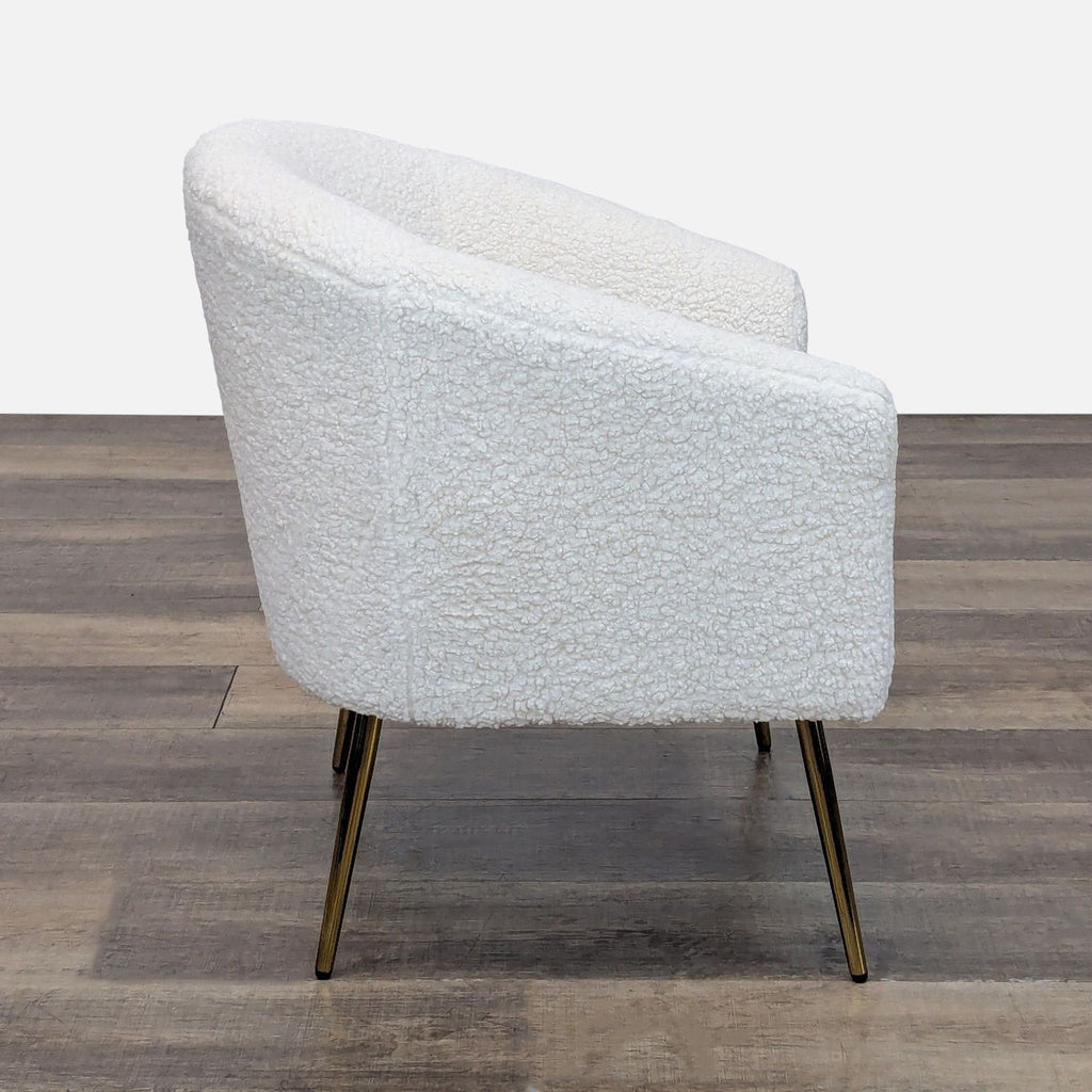 Side view of boucle upholstered armchair with gold finished legs.