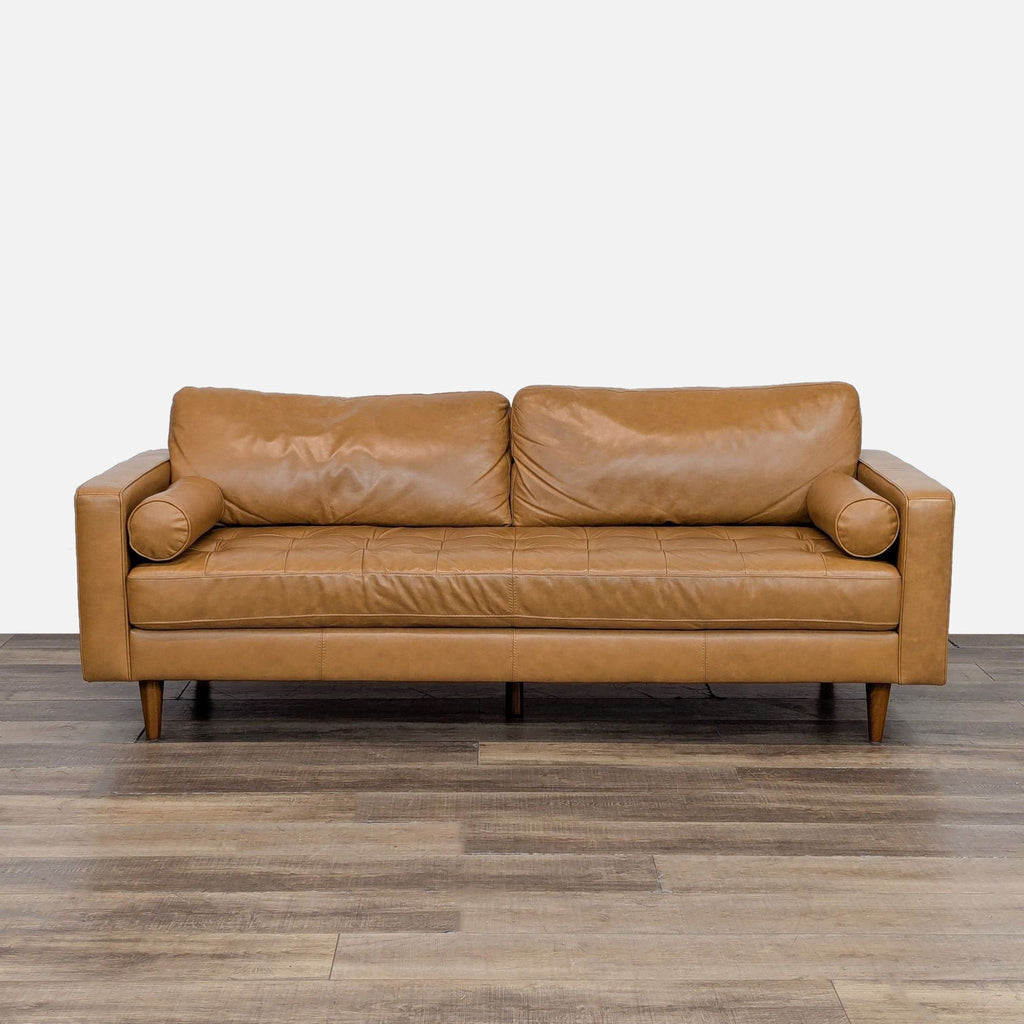 Mid-century modern sofa with track arms and tufted seats, featuring bolster pillows and tapered wood legs.