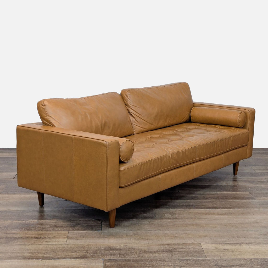 Tan leather sofa with bolster pillows and tufted seats, part of Living Spaces' 3-seat collection.