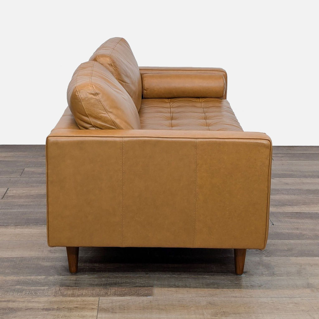 Side view of a 3-seat sofa in brown leather with track arms and tapered wooden legs.