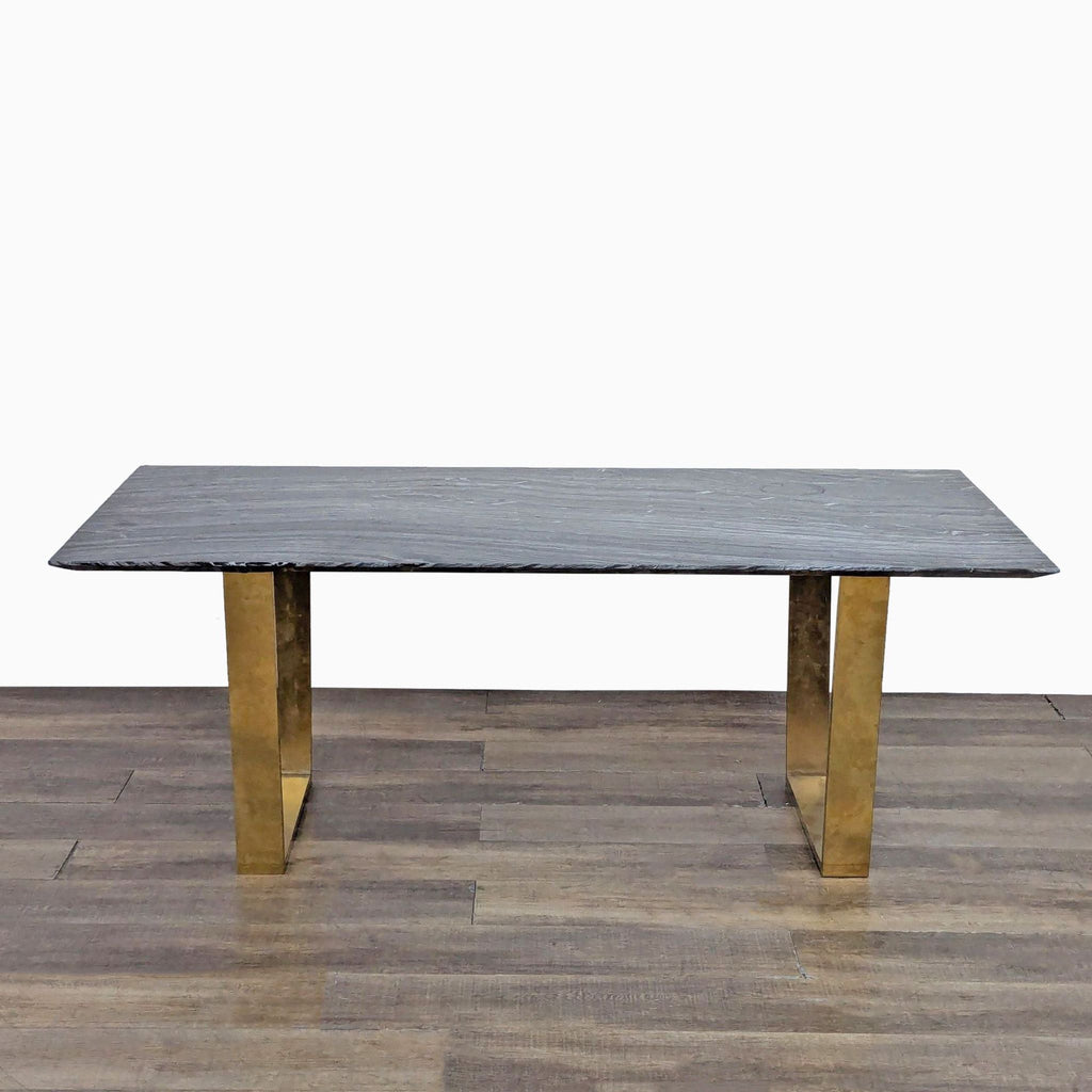 Dining table with black marble top and gold sled legs.