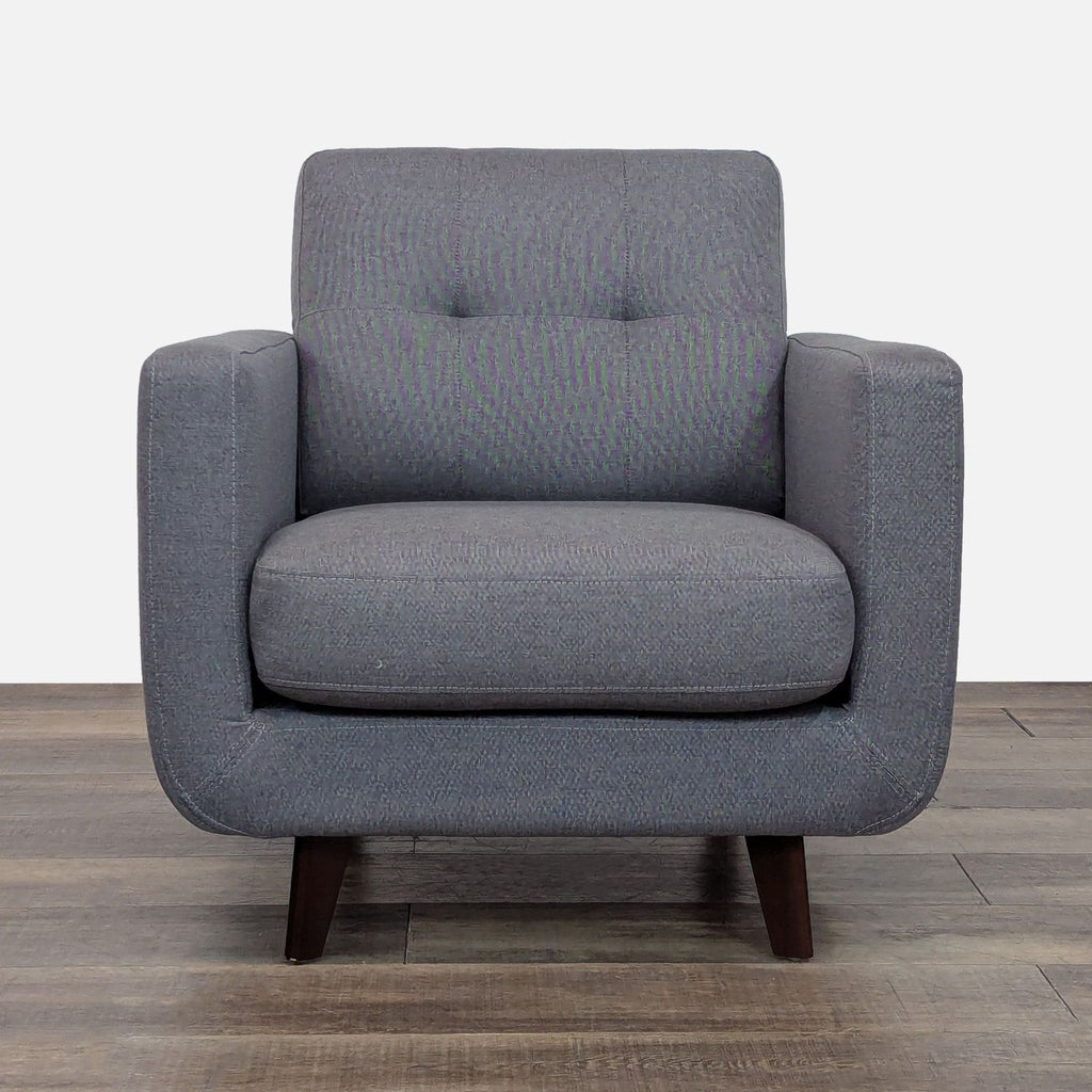 Gray tufted lounge chair with curved lines and tapered wood legs.