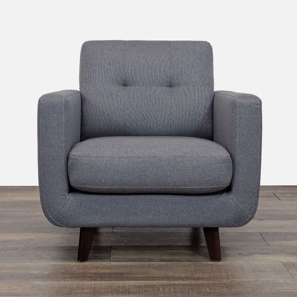 Gray tufted lounge chair with curved lines and tapered wood legs.