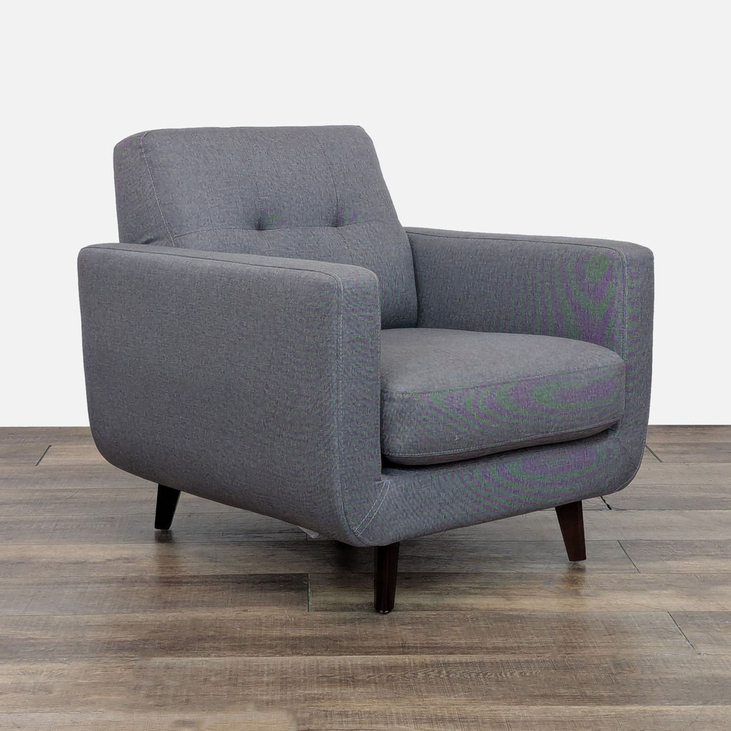 Angled view of a gray chair featuring a tufted back and wood legs.