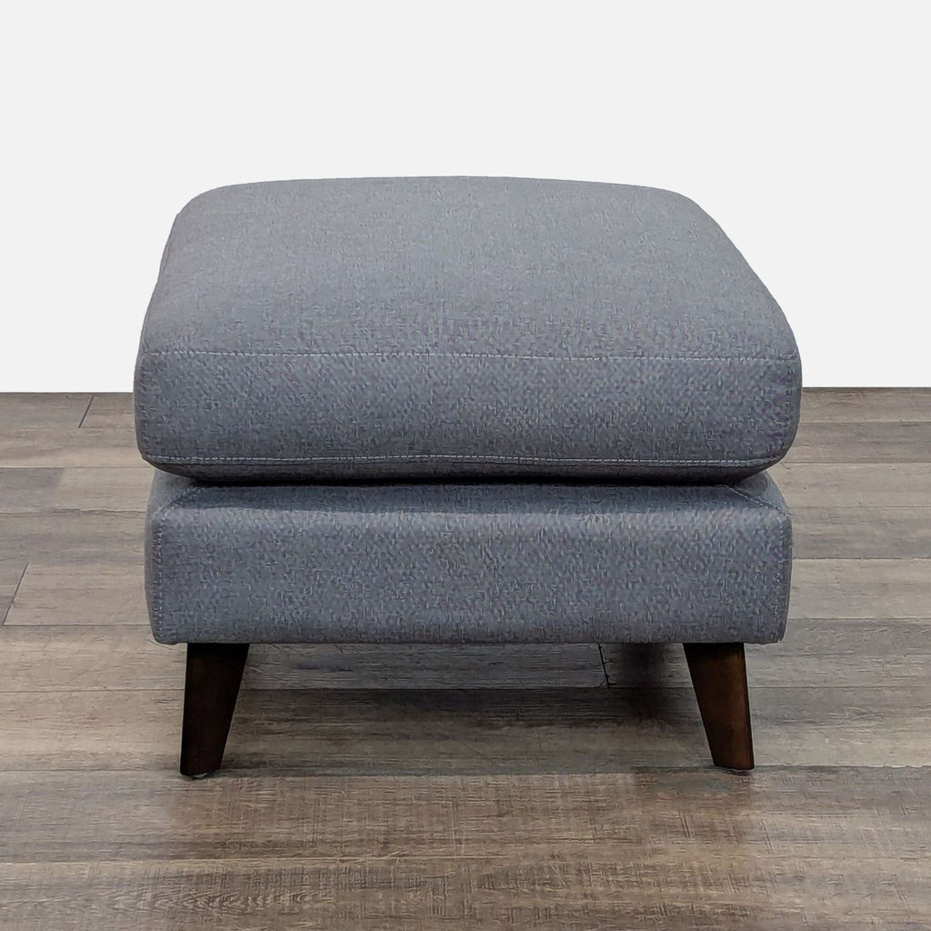 Gray Living Spaces ottoman with clean lines, suitable for seating or decor.