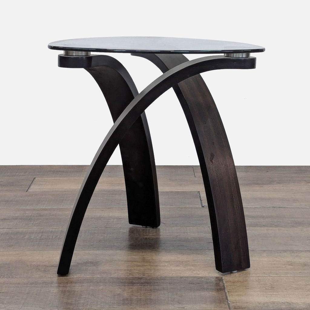 Side table with a tempered glass top and hardwood legs on wooden flooring.