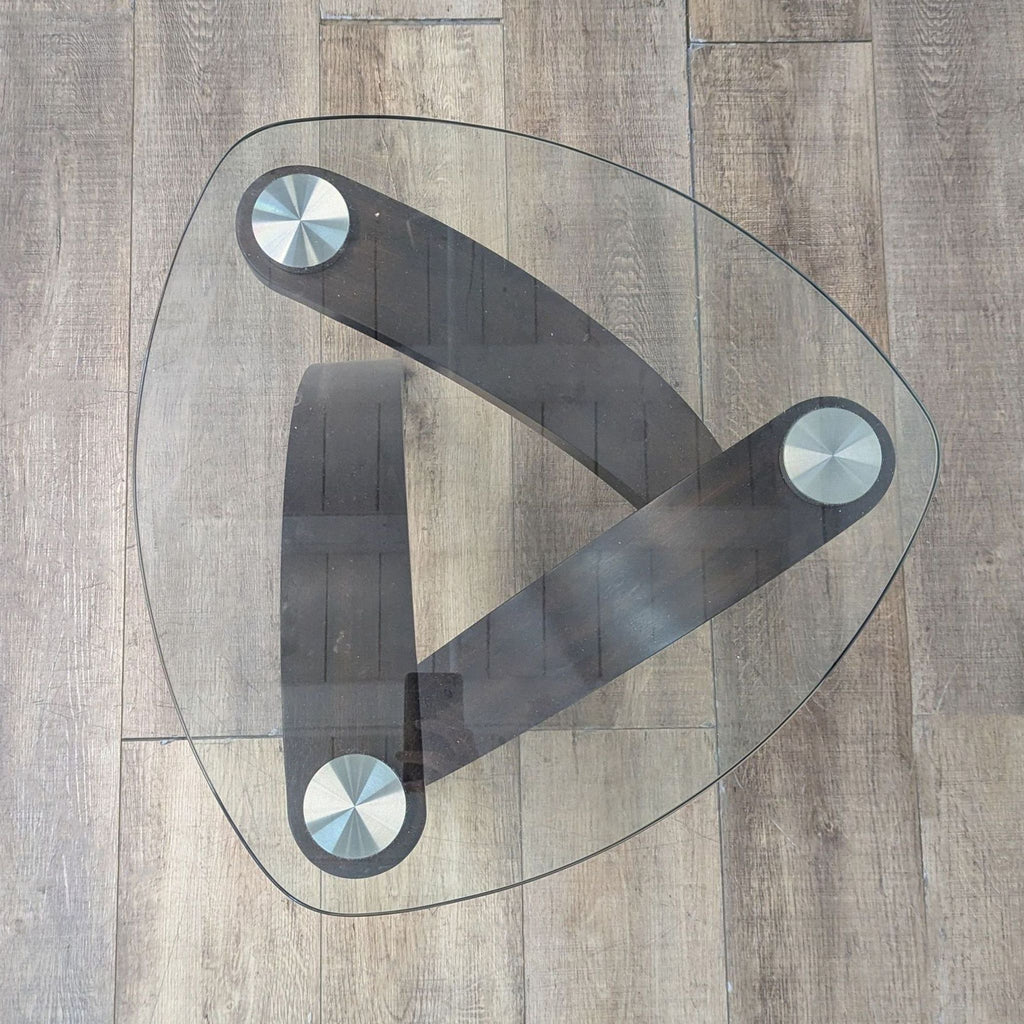 Top view of a glass table highlighting its unique triangular form and leg attachments.
