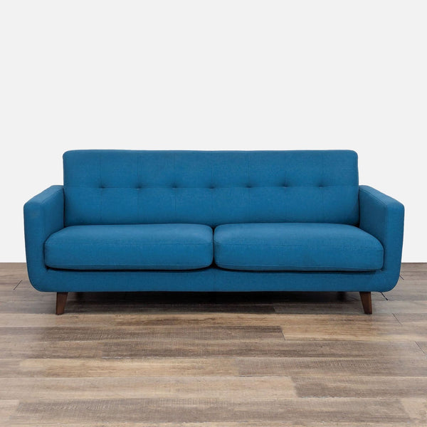 Blue tufted loveseat with fabric upholstery and tapered wood legs.