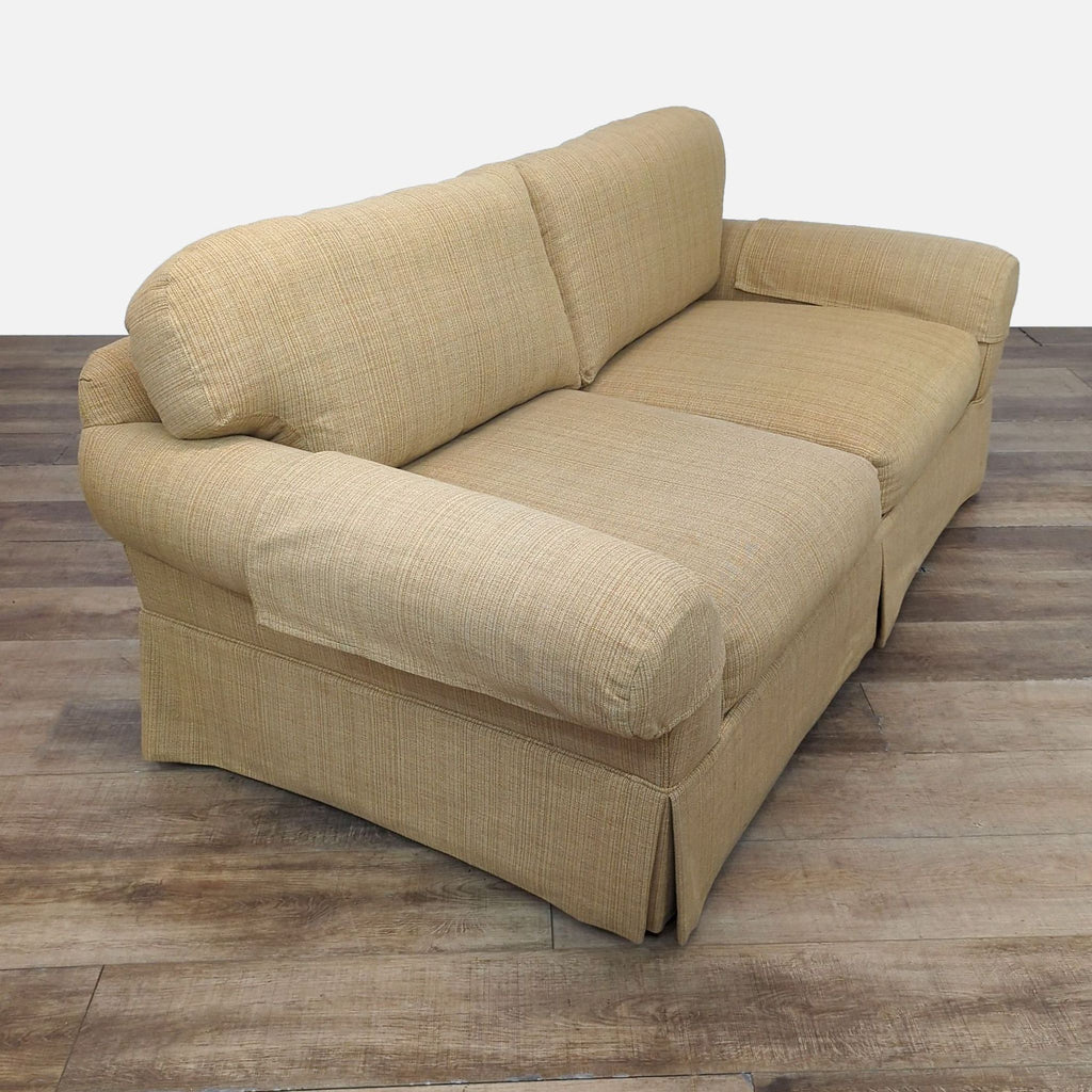 Side view of a tan loveseat featuring rolled arms and plush seating.