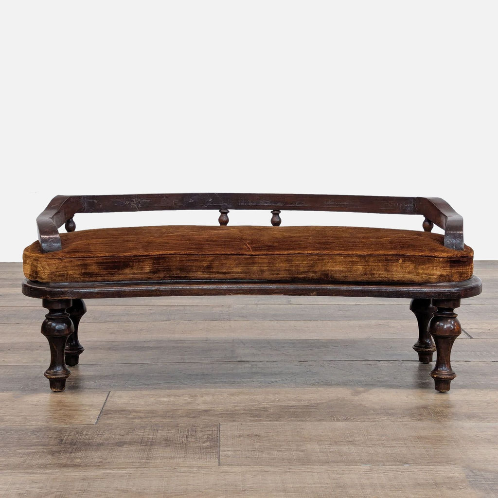 Dark brown upholstered bench with wooden backrest, featuring elegant carved legs on a wooden floor.  