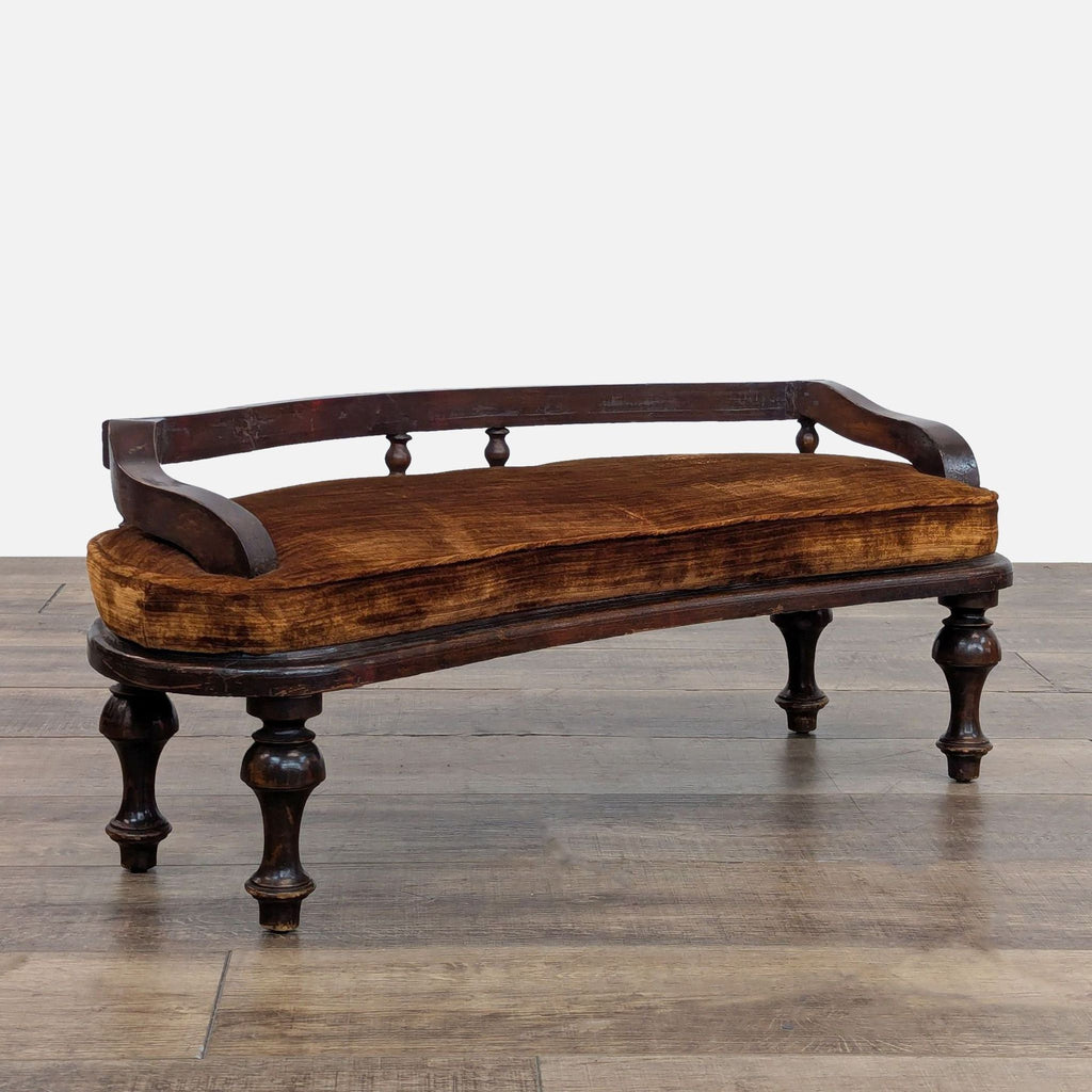Side view of a velvet cushioned bench with distinctive dark wood legs, showcased on a wooden floor.