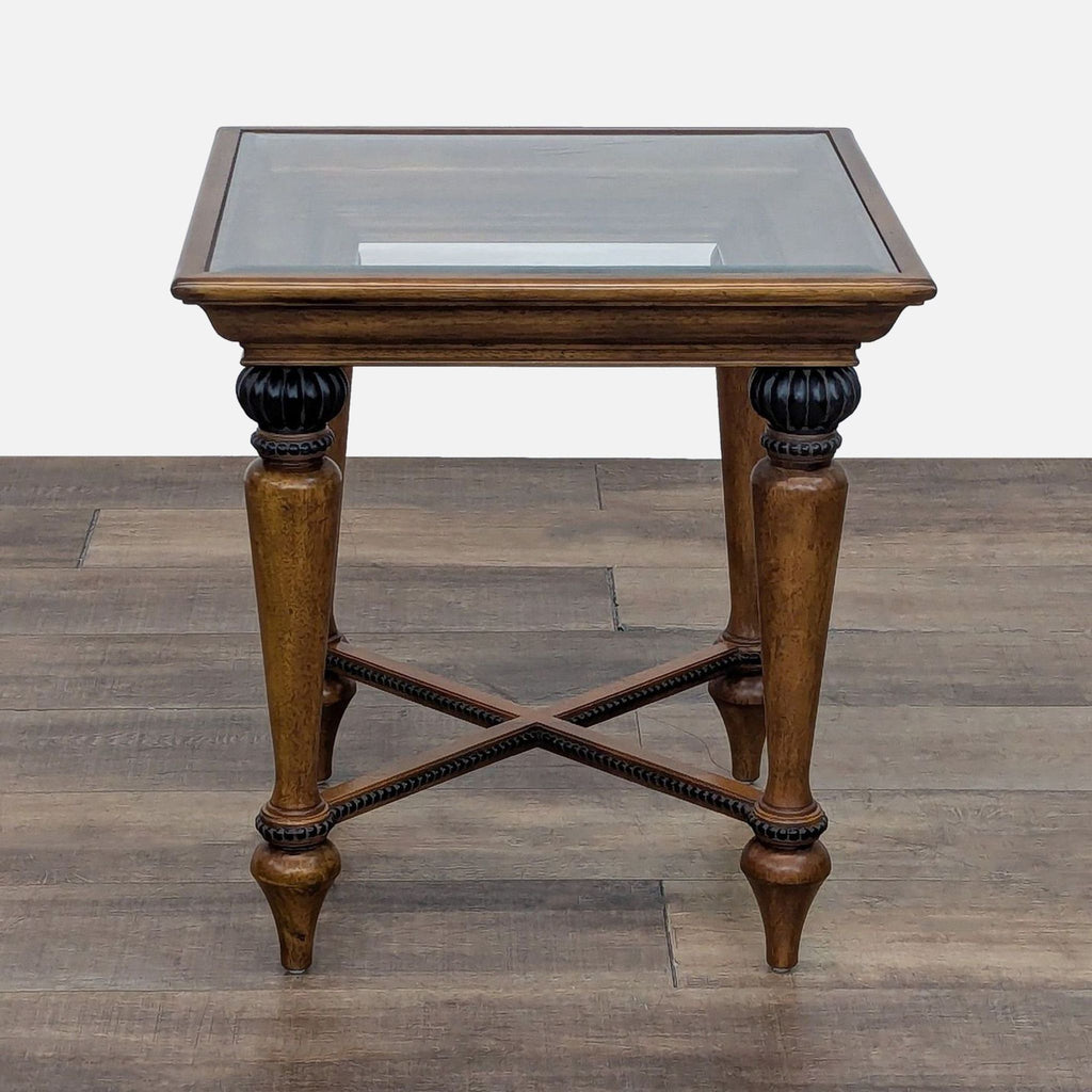 Carved wood table with bead-trimmed top and braced legs on wooden floor.