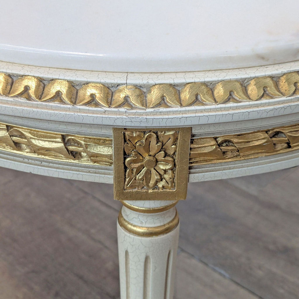 Close-up of a French table's gold-accented foliate apron and fluted leg.