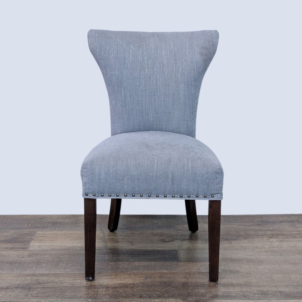 Dining chair with a tapered back, wood legs, and nailhead trim by Reperch.