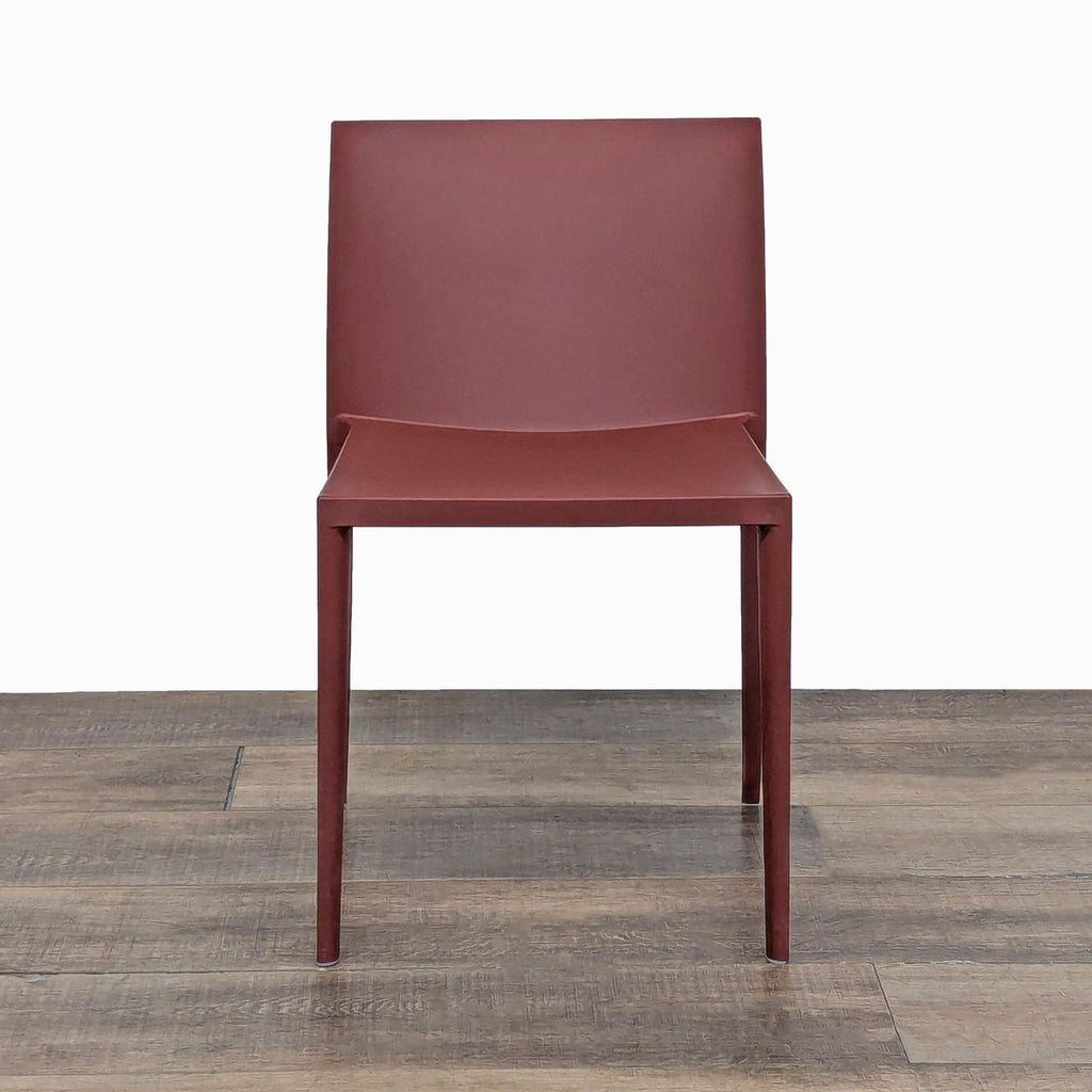 Front view of a red plastic stackable chair by Andreu World on wood floor.