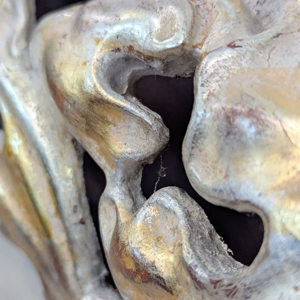 Detailed view of swirling carvings on white gold mirror frame.