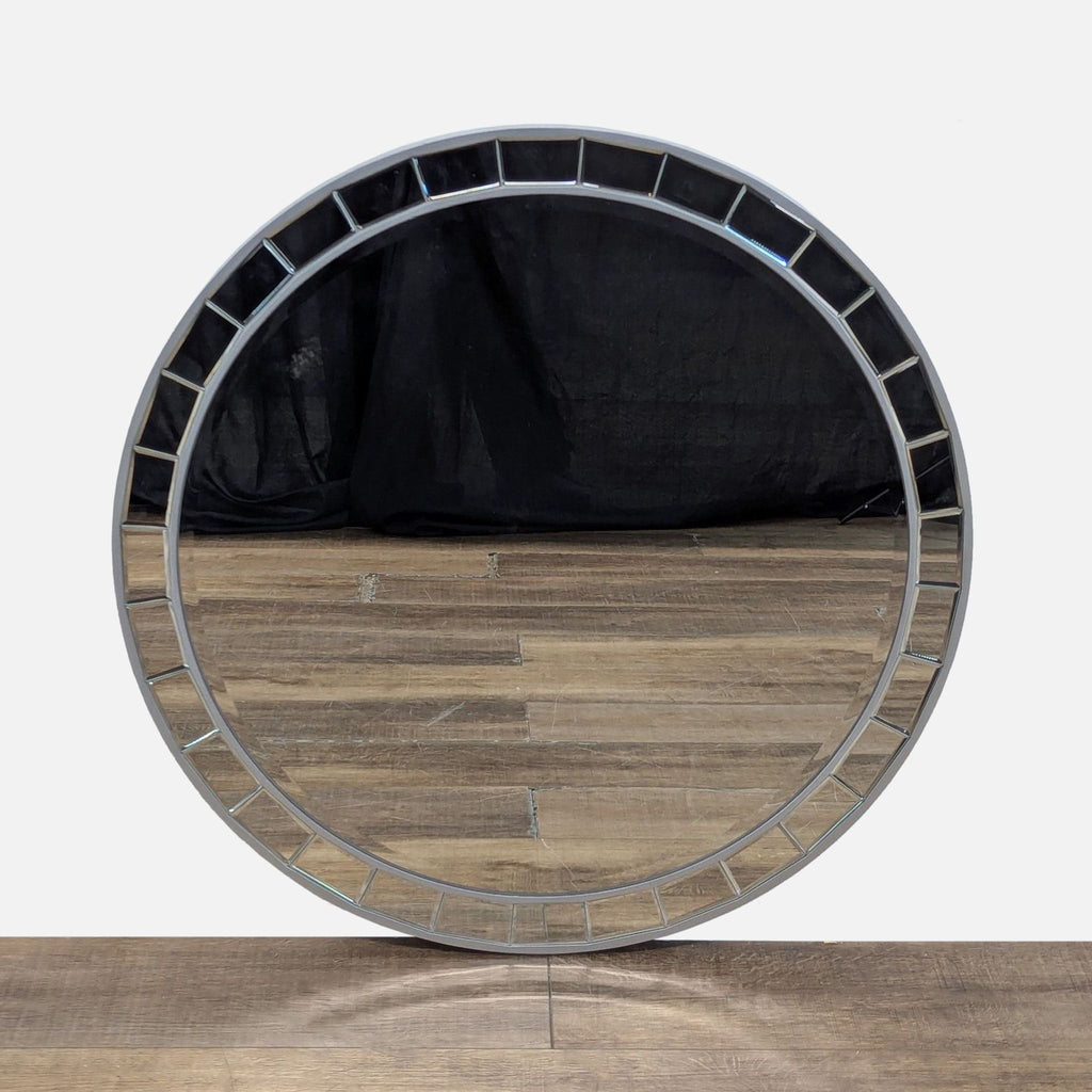 Round Possini mirror with a beveled edge and geometric pattern over wooden flooring.