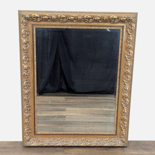 Elegant Reperch mirror with ornate gold frame reflecting a black backdrop.