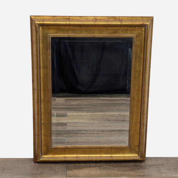 Square mirror with a gold-toned wooden frame, displaying a simple and elegant design.
