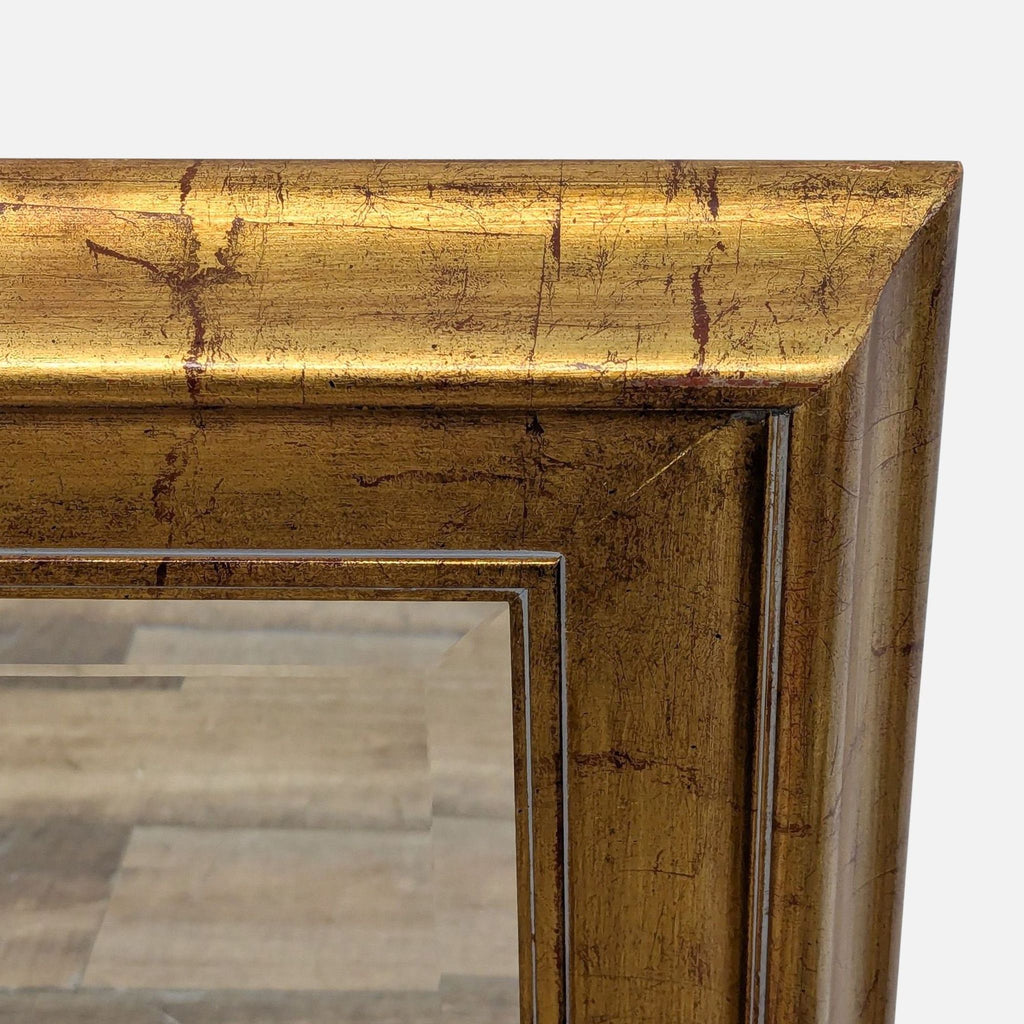 Close-up of the mirror's textured gold frame, highlighting the detailed craftsmanship.