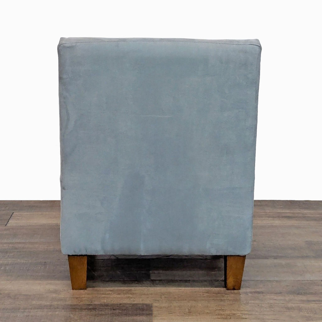 Back view of a tufted lounge chair featuring soft upholstery and wood legs.