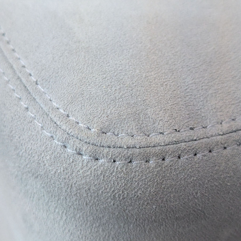 Close-up of light blue suede fabric with detailed stitching.