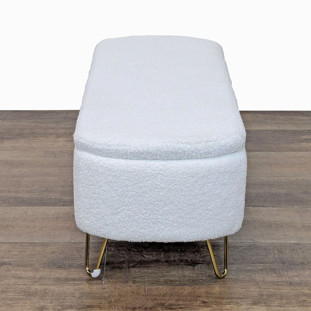 Side view of Reperch ottoman with gold legs and textured white fabric.
