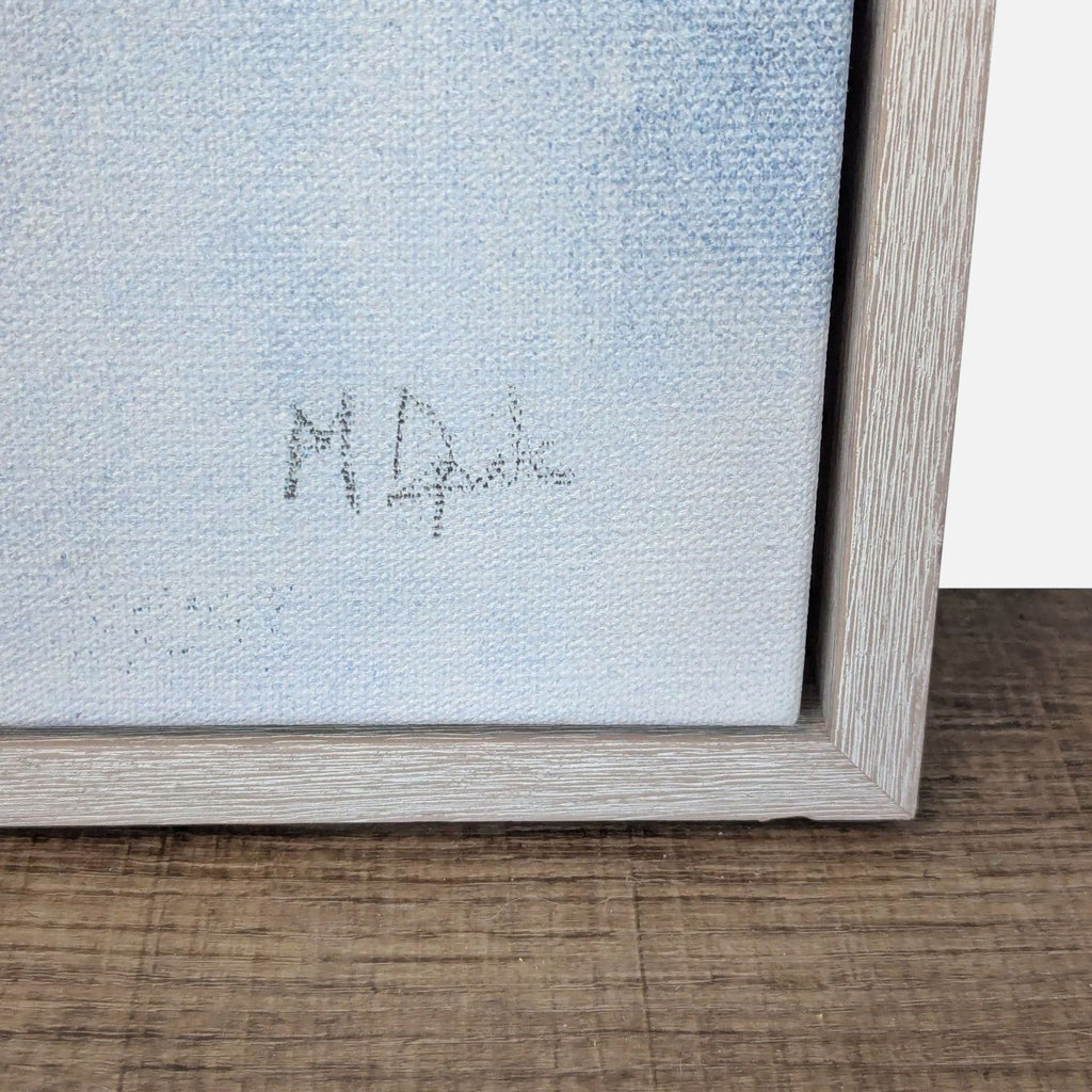 Close-up of a signature on a framed canvas painting.