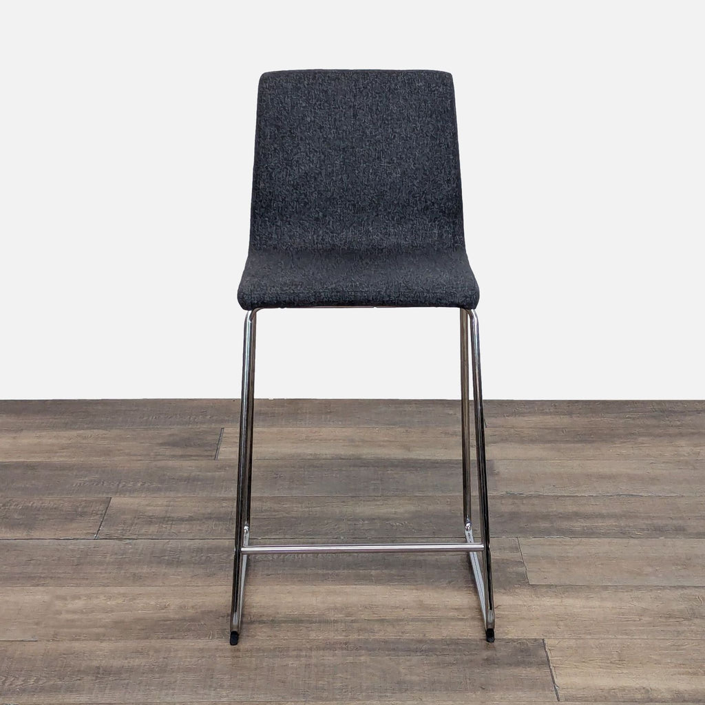 Gray upholstered stool with metal legs from Reperch, front view.